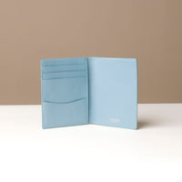 Light blue wallet open to show interior compartments on a neutral background.