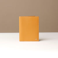 Yellow wallet on a white surface with a beige background