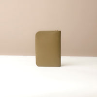 Back view view of a Danilos green passport case lovable on a beige background