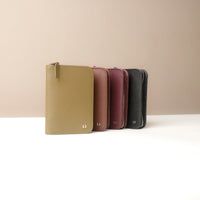 Four Danilos passport case lovable with zipper in different colors arranged in a row on a beige background