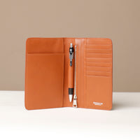 Front view of a open danilos travel pro passport case lux in brown leather with 8 card slots a zipper compartment, a pen and 1 passport slot in brown pebble leather in a beige background