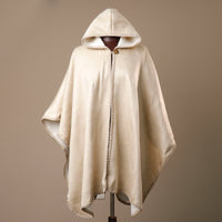 Beige hooded cape on a mannequin against a brown background