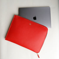 A red leather document folder resting on a laptop, highlighting its use for storing documents.