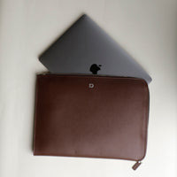 A brown leather document folder resting on a laptop, highlighting its use for storing documents.