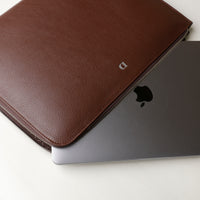 A brown leather document folder resting on a laptop, highlighting its use for storing documents.