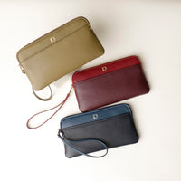Three leather pouches in green, red, and blue colors with zipper closures and a brand logo on the front.