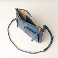 Blue handbag with gold accents on a light beige background