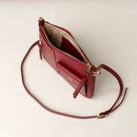 Red handbag with gold accents on a light beige background