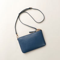 Blue handbag with a strap on a light beige background