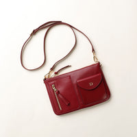 Red handbag with a gold zipper on a light beige background
