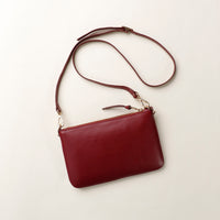 Maroon leather crossbody bag on a light beige background