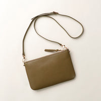 Green leather handbag with a strap on a light beige background