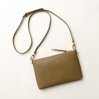 Olive green handbag with a strap on a light beige background