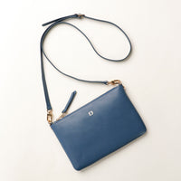 Blue crossbody bag with a strap on a light beige background