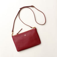 Red handbag with a gold zipper on a light beige background