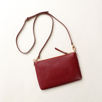 Red leather crossbody bag on a light beige background