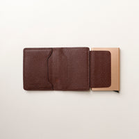 Brown leather wallet with a cardboard backing on a light beige background