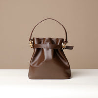 Brown leather handbag with a strap on a beige background