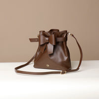Brown leather bag with a bow on a beige background
