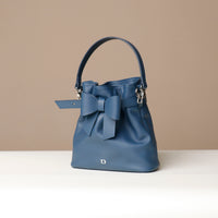 Blue handbag with a bow on a beige background