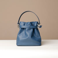 Blue handbag with a belt detail on a beige background