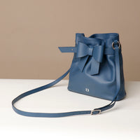 Blue handbag with a bow on a beige background
