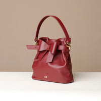 Red handbag with a bow detail on a beige background