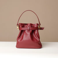 Red handbag with gold chain detail on a beige background
