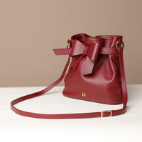 Red handbag with a bow on a beige background