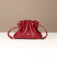 Red leather drawstring bag with a brand logo on a beige background