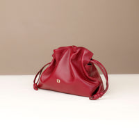 Red drawstring bag on a white surface with a beige background