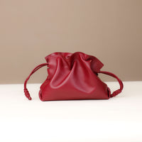 Red leather handbag on a white surface with a beige background