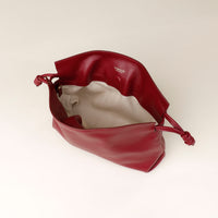Red leather handbag with drawstring on a beige background