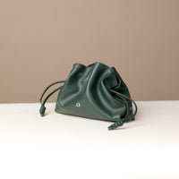 Green drawstring bag on a white surface with a beige background
