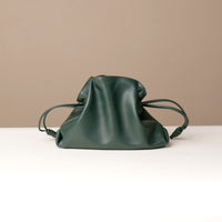 Green leather drawstring bag on a beige background