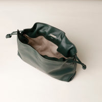 Green drawstring bag with 'Danilos' branding on a light beige background