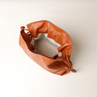 Brown leather handbag on a light beige background