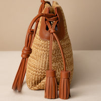 Sassy Satchel 26 Raffia Pana handcrafted with raffia and premium leather, with a pana leather strap, in a beige background, lateral view