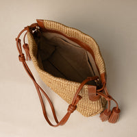 Open view of a Sassy Satchel 26 Raffia pana handcrafted with raffia and premium leather, with a leather strap, in a beige background
