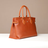 Angled view of whiskey brown Saule Tote – structured silhouette with side strap and premium stitching