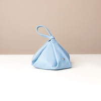 Light blue handbag on a white surface with a beige background
