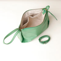 Green handbag with a detachable strap on a white background