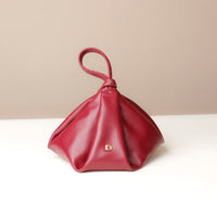 Red handbag with a knot detail on a beige background