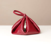 Red handbag on a white surface with a beige background
