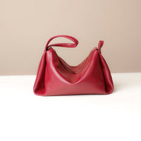 Red handbag on a white surface with a beige background
