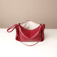 Red handbag on a white surface with a beige background