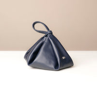 Navy blue handbag with a knot detail on a beige background