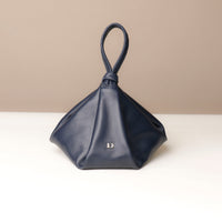 Navy blue handbag with a handle on a beige background