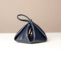 Navy blue handbag with a unique design on a beige background