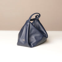 Blue handbag on a white surface with a beige background